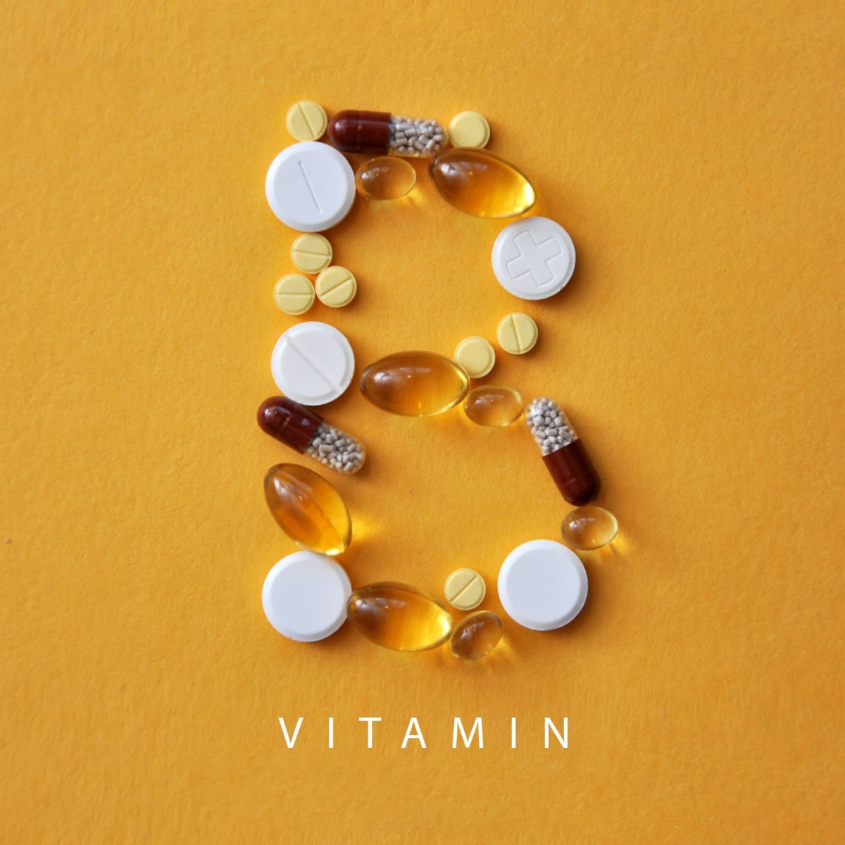 An assortment of colorful vitamins and supplements is arranged to form the letter