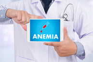A doctor in a white coat holds a tablet displaying the word "ANEMIA" with a syringe and blood drop graphic, emphasizing the topic of iron-deficiency anemia among older adults.