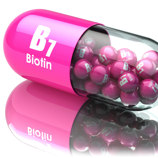 A pink capsule labeled "B7 Biotin" is partially open, revealing shiny pink and black balls inside, reflecting on a smooth surface, emphasizing its focus on biotin supplements.