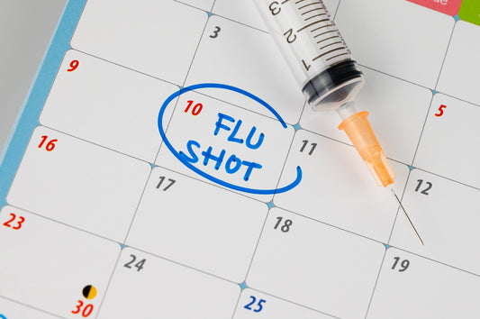 A calendar page shows the date 10 circled with the words "FLU SHOT" written in blue, next to a syringe, emphasizing the importance of scheduling flu vaccinations.