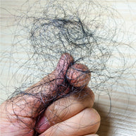 A hand holds a tangled mass of dark hair strands against a light wooden surface, illustrating the issue of temporary hair loss.