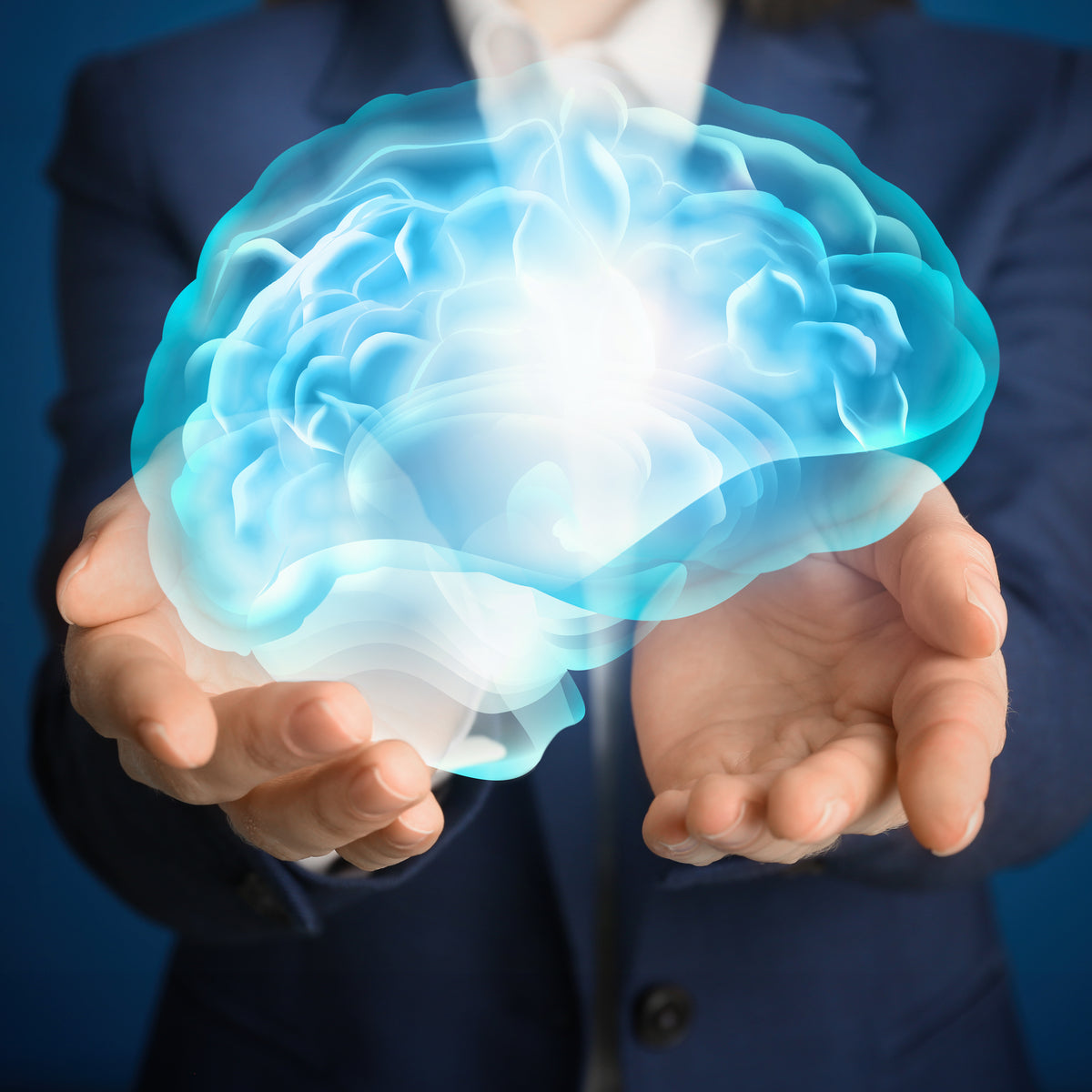 A person in a suit holds a glowing, blue brain in their hands against a dark blue background, symbolizing concepts related to memory retention and cognitive enhancement.