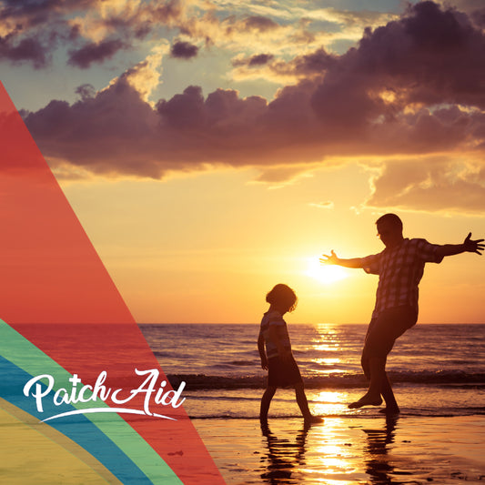 A silhouetted adult and child play joyfully at the beach during sunset, with vibrant clouds and water reflecting warm hues, symbolizing health and happiness.