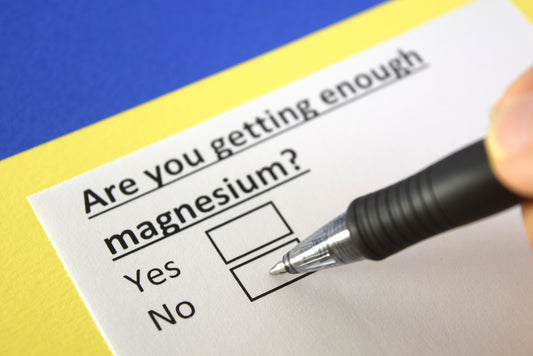 A hand holding a pen marks a checkbox on a questionnaire asking, "Are you getting enough magnesium?" with a blue and yellow background.