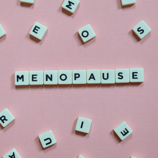 White letter tiles spell "MENOPAUSE" on a pink background, surrounded by scattered tiles, emphasizing the topic of menopause relief.