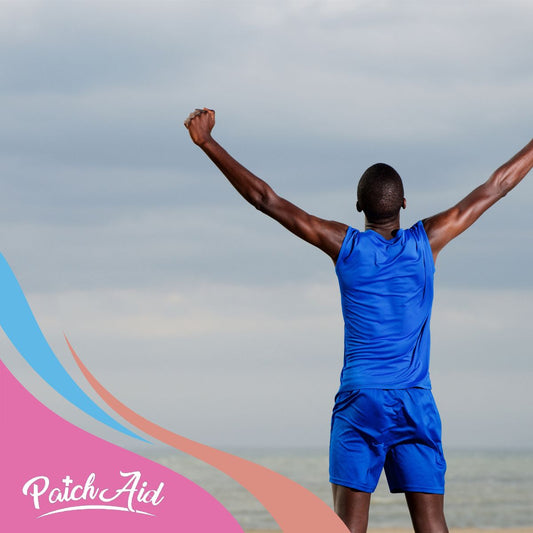 A person in a blue athletic outfit stands with arms raised in celebration against a cloudy sky, symbolizing triumph and support for long-term health in relation to chronic conditions.