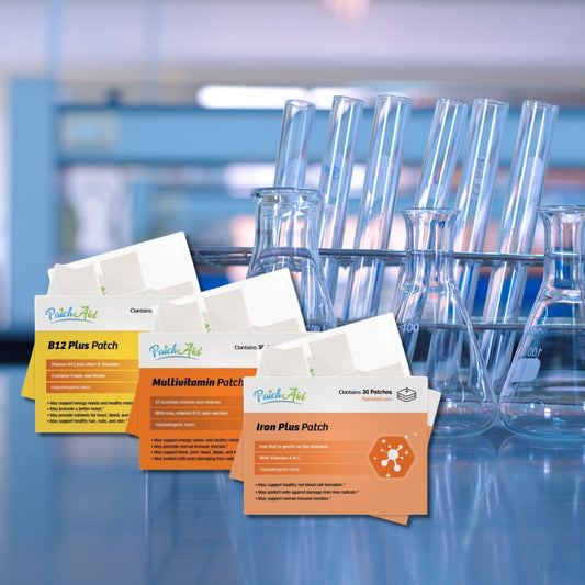 Four vitamin patches labeled B12 Plus, Multivitamin, and Iron Plus are displayed in front of laboratory glassware, highlighting their health benefits in a scientific setting.