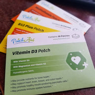 Several colorful vitamin patch packages are stacked on a wooden surface, featuring labels for Vitamin D3, B12, and other supplements, highlighting their health benefits and ingredients.