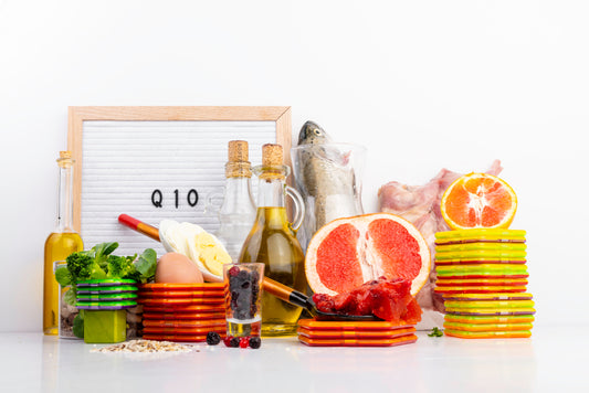 A variety of foods, including fruits, vegetables, oils, and fish, are arranged around a sign that reads "Q10," highlighting sources of CoQ10 for health benefits.