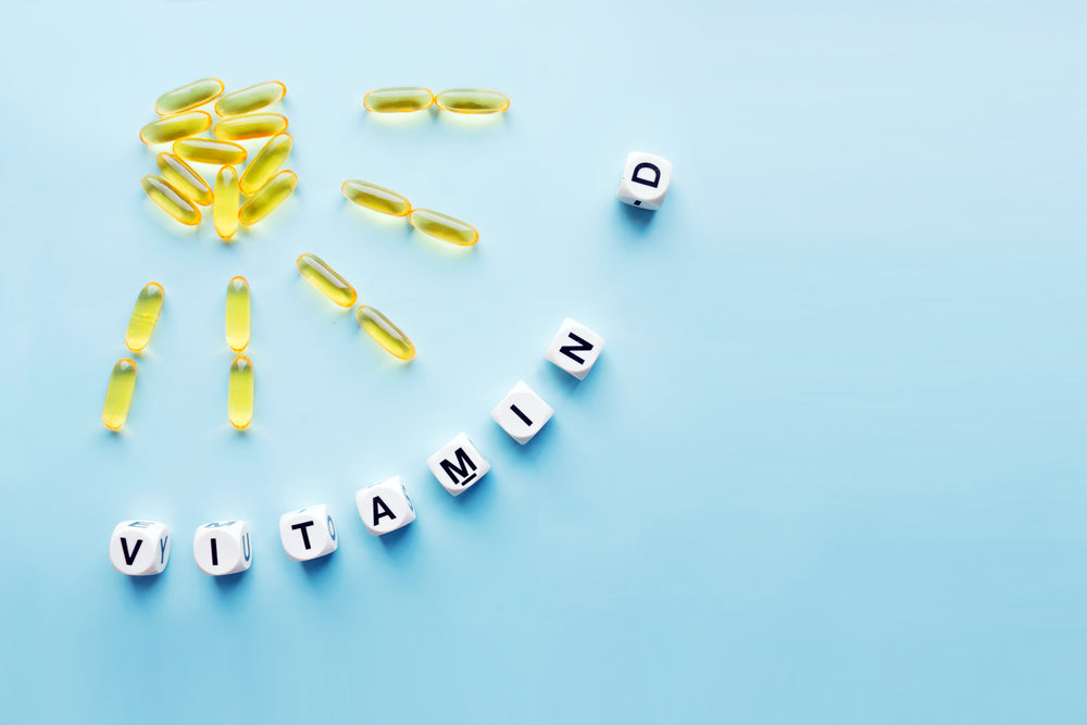 Yellow gelatin capsules are arranged in a sun shape, with white letter blocks spelling