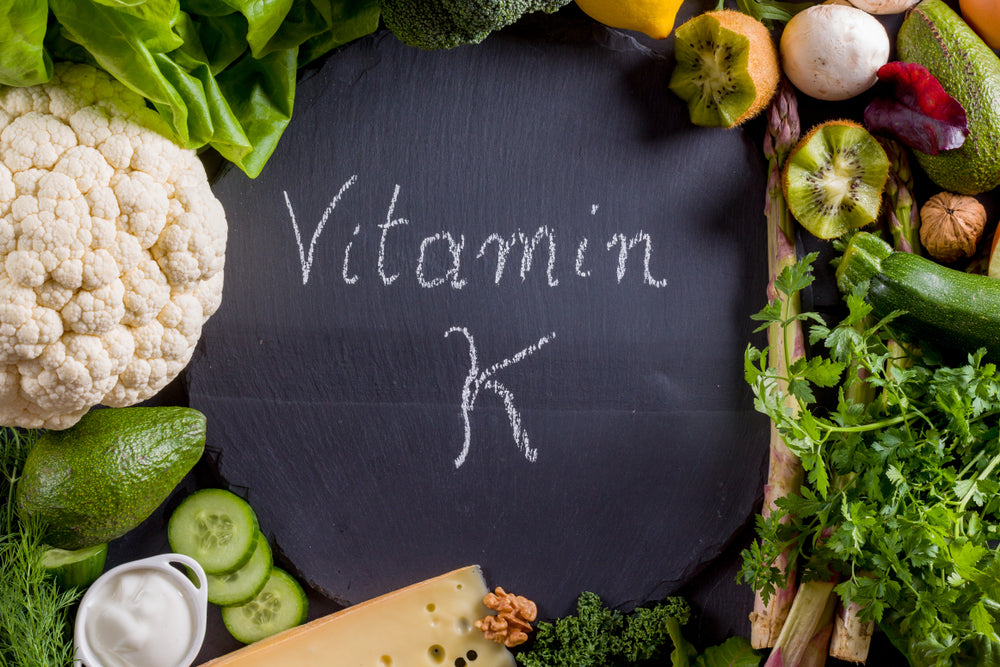 A variety of fresh vegetables and herbs surround a chalkboard with