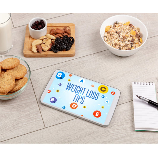 A smartphone displaying "Weight Loss Tips" is placed on a wooden surface surrounded by healthy snacks, including nuts, dried fruit, cookies, and a bowl of oatmeal, with a notepad and pen nearby.
