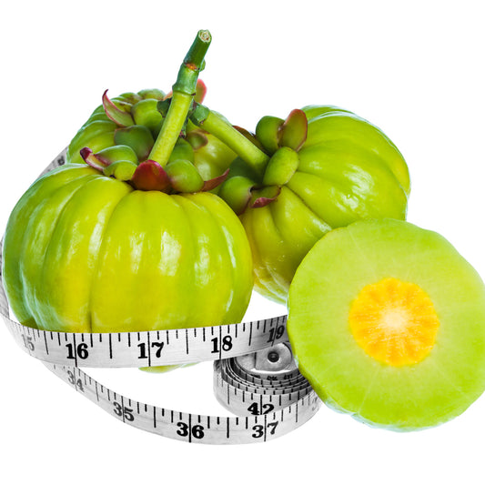 Three green Garcinia Cambogia fruits are displayed with a measuring tape wrapped around them, and one fruit is cut in half to reveal its yellow interior, emphasizing its connection to weight loss.