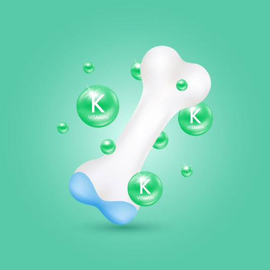 A white bone with a blue tip is surrounded by green bubbles labeled "K" for vitamin K, set against a light green background, highlighting the importance of vitamin K in bone health.