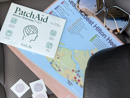 PatchAid motion sickness patch packaging placed on a travel map with sunglasses and loose patches nearby, representing convenient on-the-go nausea and dizziness support for travel.