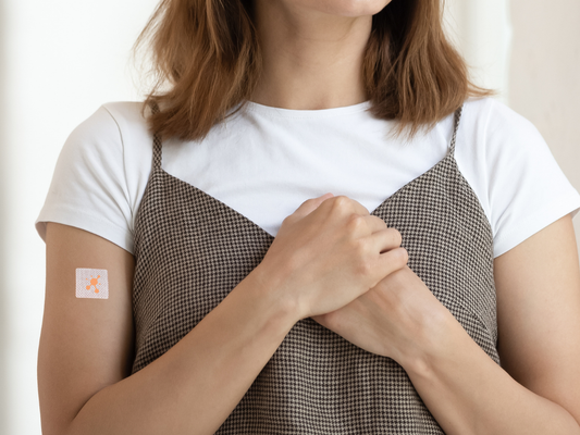 Person wearing a PatchAid vitamin patch on their upper arm, with hands resting over their chest, representing a simple, wearable daily wellness routine.