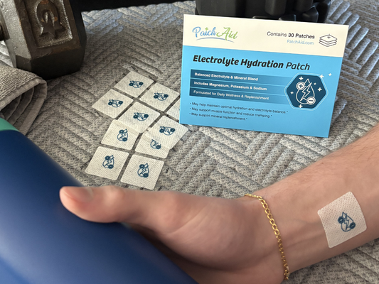 Electrolyte hydration patch applied to a person’s wrist, with multiple unused patches and PatchAid packaging visible in the background, highlighting daily wellness and hydration support.
