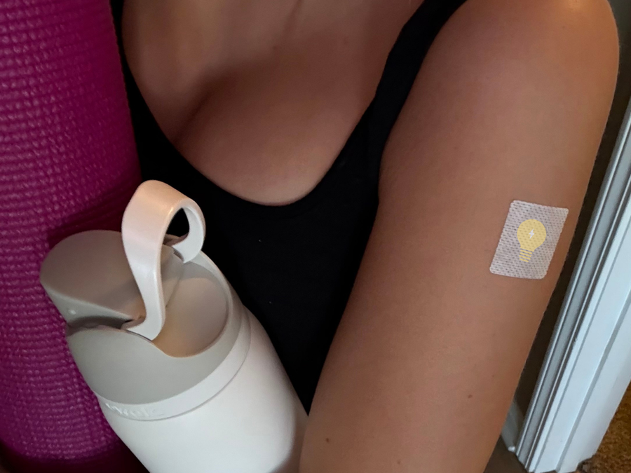 Person wearing a vitamin patch on arm after workout with water bottle nearby
