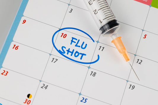 A calendar page shows the date 10 circled with the words "FLU SHOT" written in blue, next to a syringe, emphasizing the importance of scheduling flu vaccinations.