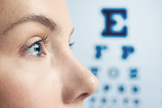 A close-up of a person's eye looking towards an eye chart in a clinical setting, emphasizing the importance of vision testing and eye health.