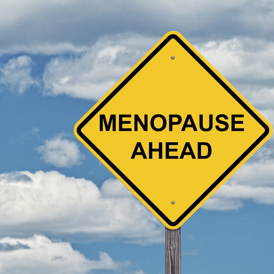 A yellow diamond-shaped sign displays the text "MENOPAUSE AHEAD" against a backdrop of blue sky and clouds, suggesting a humorous warning about menopause.