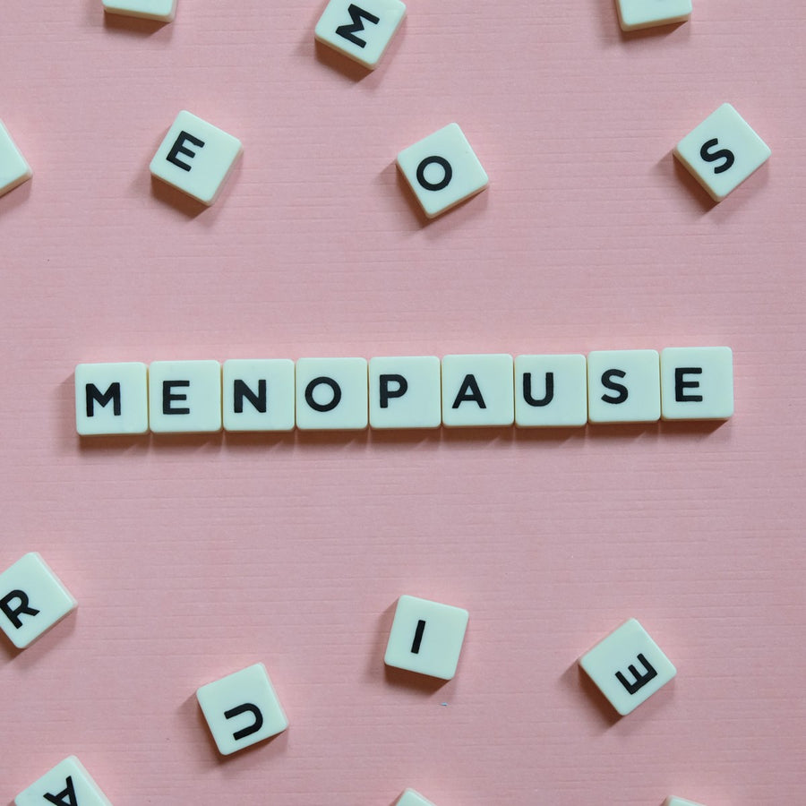 White letter tiles spell "MENOPAUSE" on a pink background, surrounded by scattered tiles, emphasizing the topic of menopause relief.