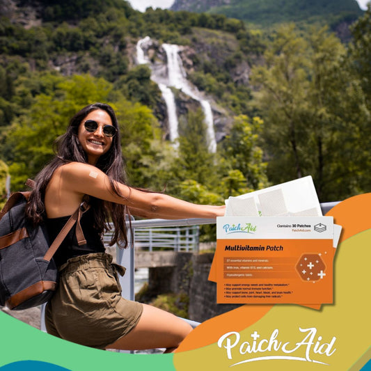 A smiling woman with long hair and sunglasses sits by a railing in front of a waterfall, showcasing a multivitamin patch on her arm and a box of patches beside her.