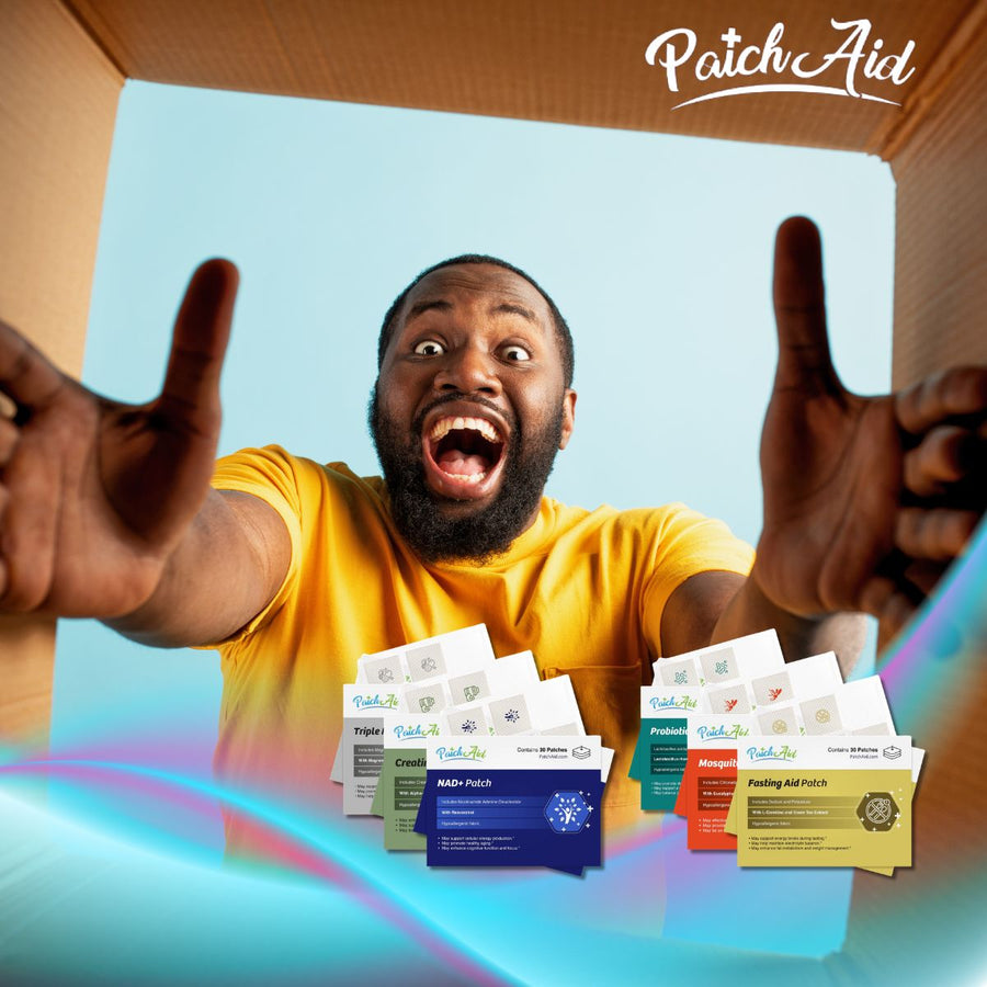 A man in a yellow shirt excitedly holds his arms out while smiling widely, surrounded by colorful vitamin patches from PatchAid, inside a cardboard box against a light blue background.