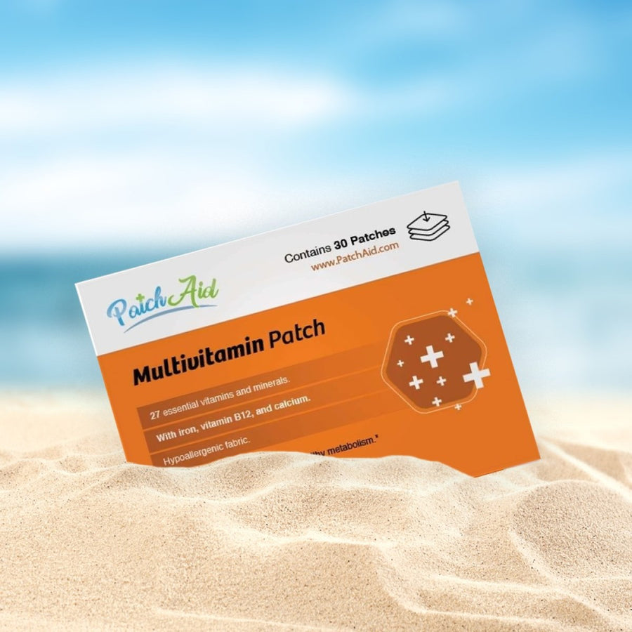 A multivitamin patch package is partially buried in sandy beach terrain, featuring an orange design with text highlighting its 27 essential vitamins and minerals, including iron and calcium.