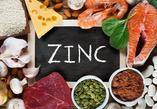 A variety of foods rich in zinc, including meat, seafood, nuts, and vegetables, surround a chalkboard displaying the word "ZINC," highlighting its importance for immune health.